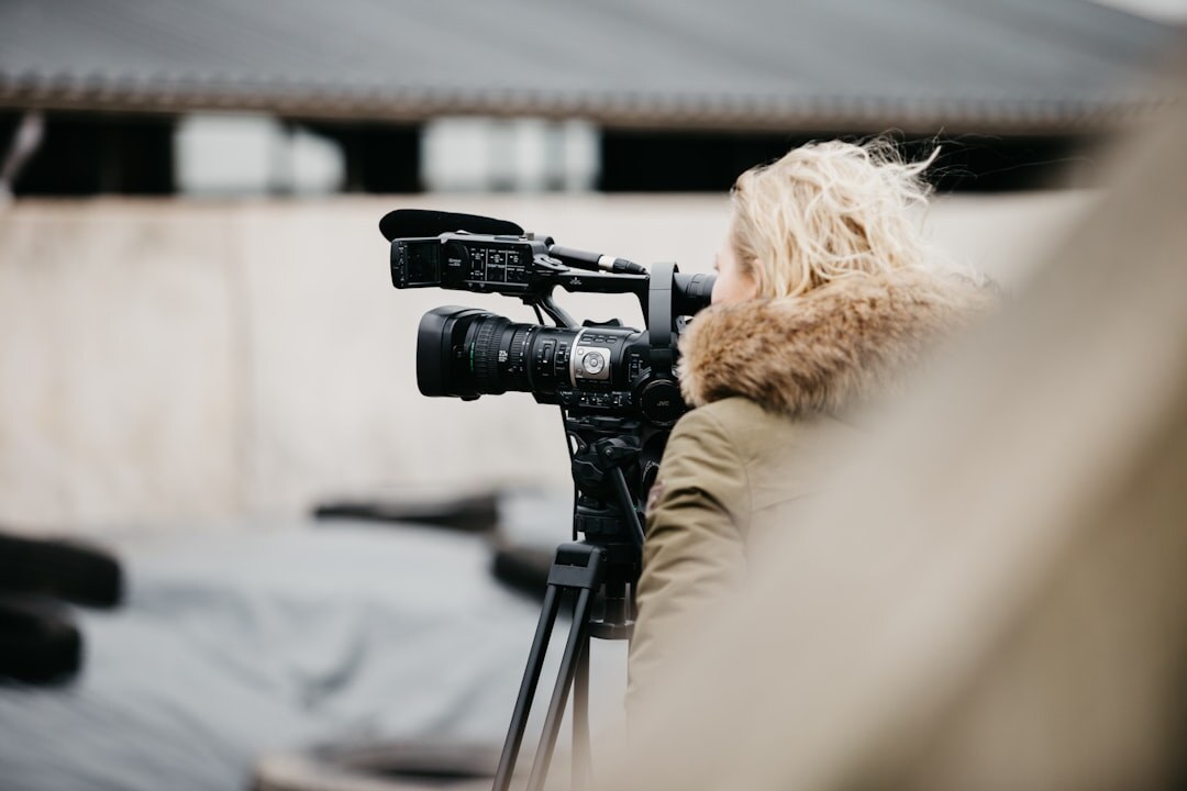 Camera operator adjusting professional camera on tripod